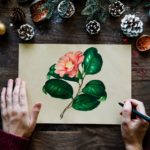 This is a photo from above of an artist working on a drawing of a flower