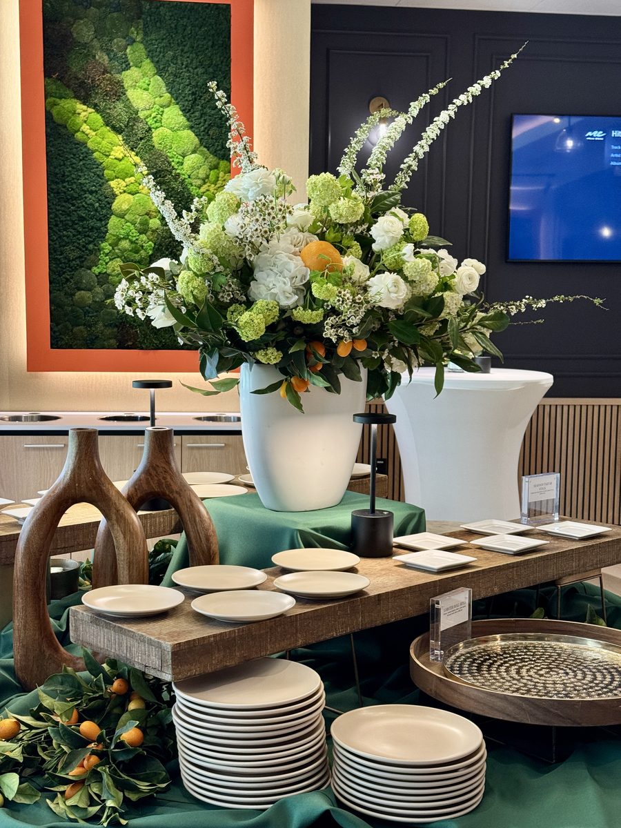 Elegant IPO celebration buffet setup with floral centerpiece and fine dining plates by Handheld Catering