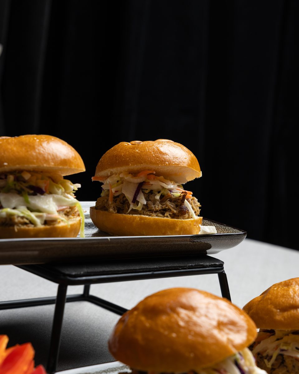Pulled pork sliders with coleslaw on a tiered serving stand at a Handheld Catering small party