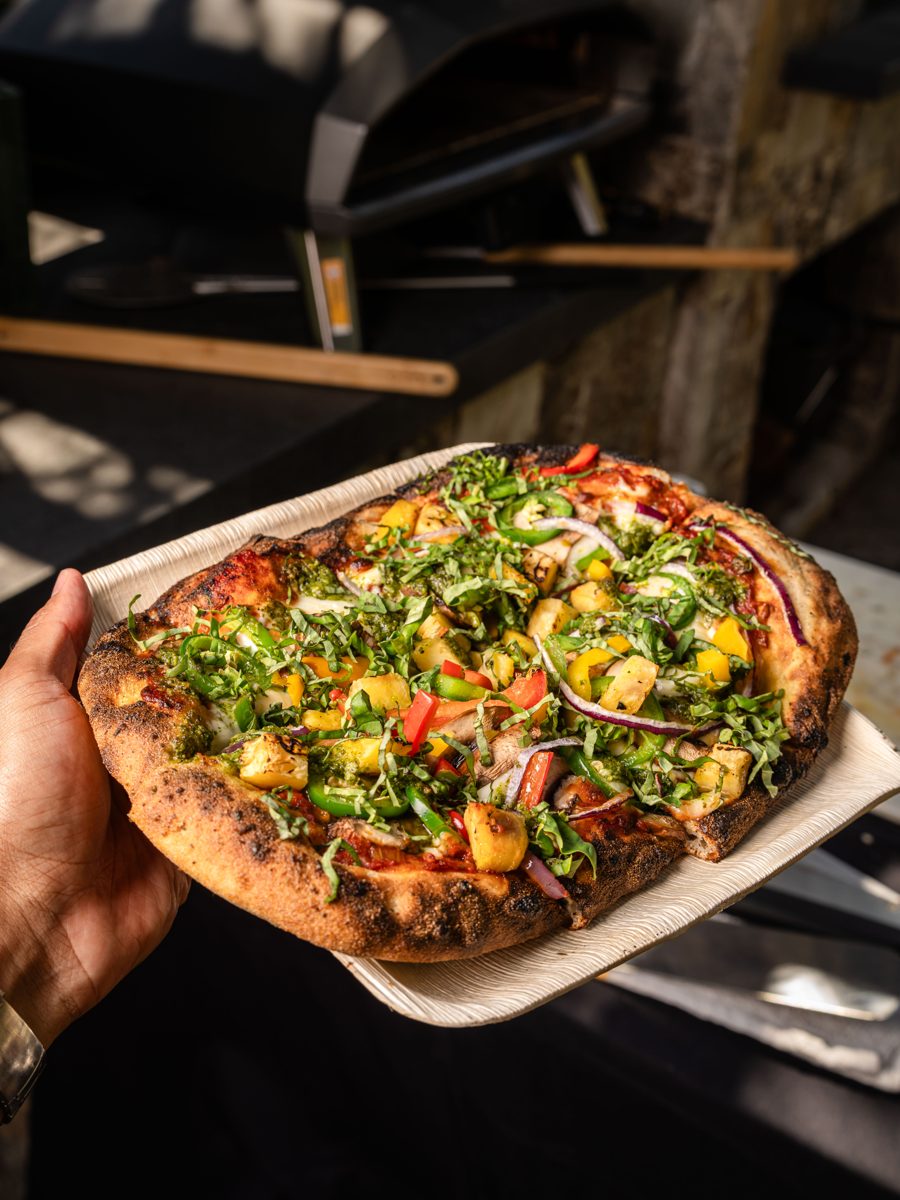 Wood-fired artisan pizza topped with fresh ingredients on a wooden serving board at a Los Altos graduation party, catered by Handheld Catering